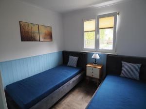 two beds in a room with blue sheets and windows at Pod Morskim Niebem in Poddąbie