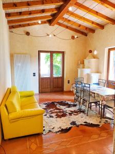 un soggiorno con divano giallo, tavolo e sedie di Villa Fior di Loto a Limone sul Garda