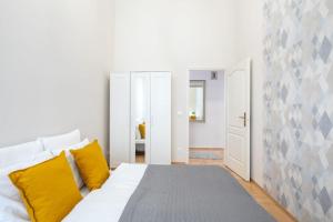 a white bed with yellow pillows in a room at Cityscape Apartments Theresa in Budapest