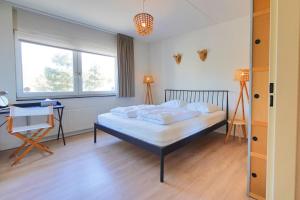 a bedroom with a bed and a desk and a window at Duinerei Groote Keeten in Callantsoog