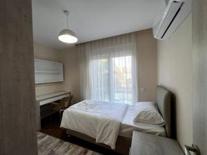 ein Schlafzimmer mit einem Bett, einem Schreibtisch und einem Fenster in der Unterkunft Şık, merkezde denize 3 km Kültür kafeler cd. 2 dk '12' in Antalya