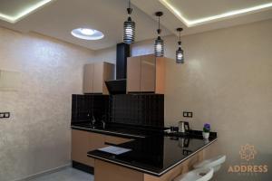 a kitchen with black counter tops and brown cabinets at Bella Address Hotel Beach in Saïdia