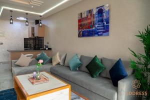 a living room with a gray couch with blue pillows at Bella Address Hotel Beach in Saidia 