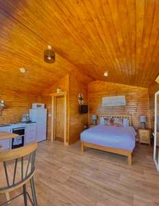 a bedroom with a bed and a wooden ceiling at Cosy Portmor Log Cabin in Malin Head