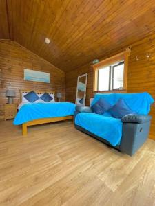 a bedroom with a blue couch and a bed at Cosy Portmor Log Cabin in Malin Head