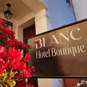 Blanc Hotel Boutique في سالتا: علامة أمام مبنى الفندق مع الزهور الحمراء