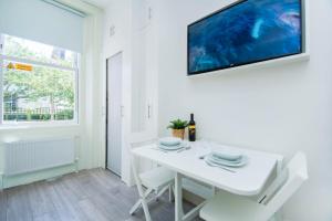 uma sala de jantar branca com uma mesa branca e uma televisão em SoBo Studio 2 - by Brighton Holiday Lets em Brighton & Hove