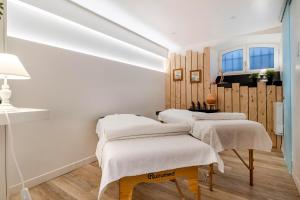 a room with three beds with white blankets at Hôtel & Espace Bien-être La Maison du Lierre in Biarritz