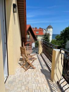 two wooden chairs sitting on the balcony of a building at Willa Bursztyn Gdansk in Gdańsk