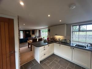cocina con armarios blancos y sala de estar. en Tanyard Cottage - Whixley, York, North Yorkshire en York