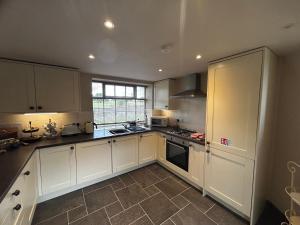 a large kitchen with white cabinets and a window at Tanyard Cottage - Whixley, York, North Yorkshire in York