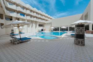 ein Hotel mit einem Pool, Stühlen und Sonnenschirmen in der Unterkunft Aqua Mondo Abu Soma Resort in Hurghada
