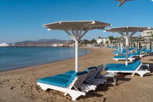 eine Gruppe von Stühlen und Sonnenschirmen am Strand in der Unterkunft Aqua Mondo Abu Soma Resort in Hurghada