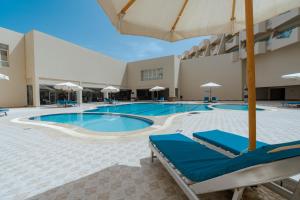 una piscina con tumbonas azules y sombrilla en Aqua Mondo Abu Soma Resort, en Hurghada