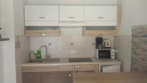 a kitchen with white cabinets and a sink and a microwave at Apartment Tuja in Jadrtovac +36 photos