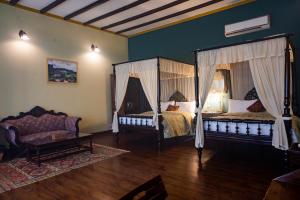 德拉敦Tree of Life Resort Dehradun Foothills的一间卧室设有两张天蓬床和一张沙发