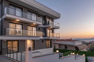 een gebouw met balkons en een zonsondergang op de achtergrond bij Çalış Suites Hotel - Family only in Çeşme