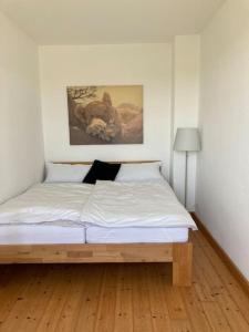 Schlafzimmer mit einem Bett mit weißer Bettwäsche und einem Bild in der Unterkunft Landidylle auf dem Rittergut in Blomberg