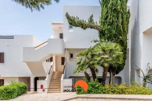 a white building with a palm tree in front of it at #174 T2 em Zona Tranquila by Home Holidays in Albufeira