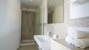 a white bathroom with a sink and a shower at Maravida Vacation Rooms in Dobrovo