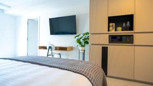 1 dormitorio con 1 cama y TV en la pared en Maravida Vacation Rooms, en Dobrovo