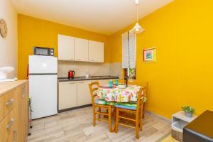 a kitchen with a table with chairs and a white refrigerator at Apartman Kovač in Malinska +26 photos