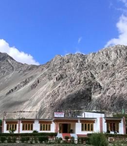 a white building with a mountain in the background at Maryoul Guest House, Hunder Nubra in Hundar