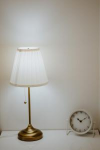 une lampe assise à côté d'une horloge sur une table dans l'établissement Apartman 007, à Vukovar