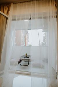 una mesa frente a una ventana con cortinas blancas en Apartman 007 en Vukovar