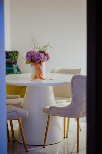 una mesa con un jarrón de flores y dos sillas en Apartman 007 en Vukovar