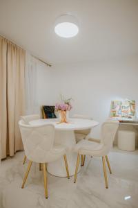 uma sala de jantar branca com uma mesa e cadeiras brancas em Apartman 007 em Vukovar