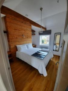 a bedroom with a large white bed with a wooden wall at Apartment 5 at Number 8: 1 bedroom, sofa bed in lounge, kitchenette & walk-in shower in Kent