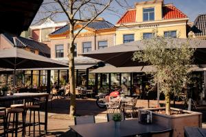 a cafe with tables and chairs and umbrellas at City Hotel de Jonge in Assen