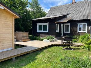 un patio trasero con terraza de madera junto a una casa en Vila Arjola en Kaltanėnai