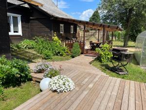 una terraza de madera con flores frente a una casa en Vila Arjola, en Kaltanėnai