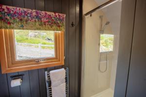 a bathroom with a shower and a window with a shower curtain at The Highland Bothies Glamping in Ullapool