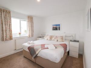 a white bedroom with a large bed with a window at Far Horizons in Newquay