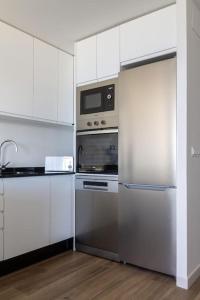 una cocina con electrodomésticos de acero inoxidable y armarios blancos en lacaletasol, en Villajoyosa
