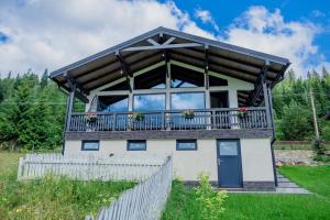 a house with a balcony and a fence at Tiny House Todireni in Vatra Dornei