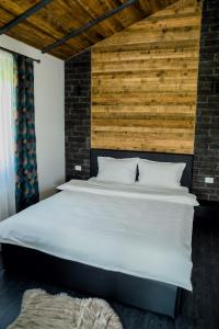a bedroom with a white bed with a wooden wall at Tiny House Todireni in Vatra Dornei