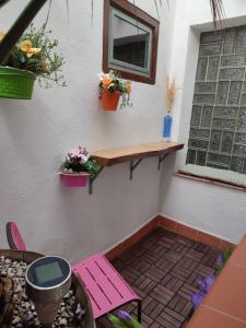 a patio with a pink bench and flowers on a wall at Casa Rural La Gineta in Calaceite