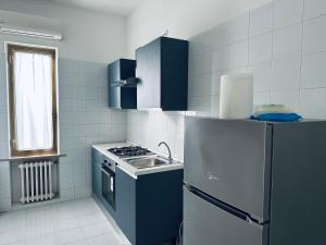 La cuisine est équipée de placards bleus, d'un évier et d'un réfrigérateur. dans l'établissement Siliade Apartment, à Montesilvano