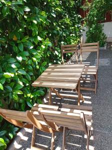 a group of wooden tables and chairs next to a bush at Aegean Breeze Beach House in Artemida