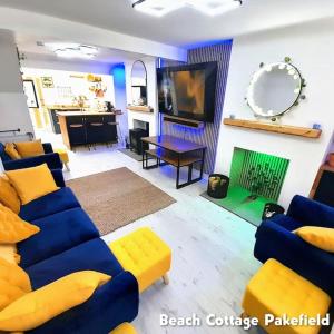 a living room with blue couches and a television at Beach Cottage Pakefield- Newly Fully Renovated House in Pakefield