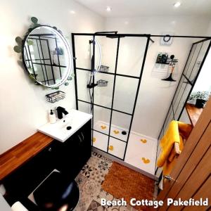 a bathroom with a sink and a shower with a mirror at Beach Cottage Pakefield- Newly Fully Renovated House in Pakefield