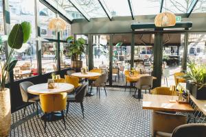 a restaurant with tables and chairs and windows at City Hotel de Jonge in Assen