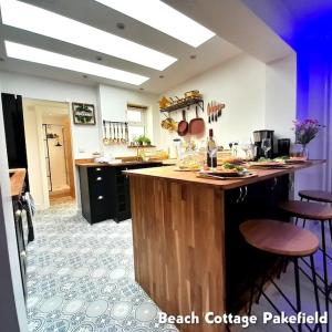a kitchen with a counter and some stools in it at Beach Cottage Pakefield- Newly Fully Renovated House in Pakefield