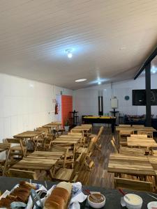 uma sala cheia de mesas e cadeiras de madeira em HOSTEL PACÍFICO em Tramandaí
