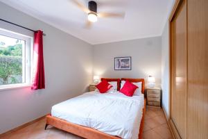 um quarto com uma cama com almofadas vermelhas e uma janela em Casa Talay 4 Bedroom Pool Villa - Meia Praia Beach, Lagos em Lagos