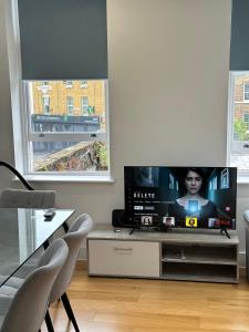 sala de estar con TV y 2 ventanas en Luxury Flat Near Greenwich Park, en Londres